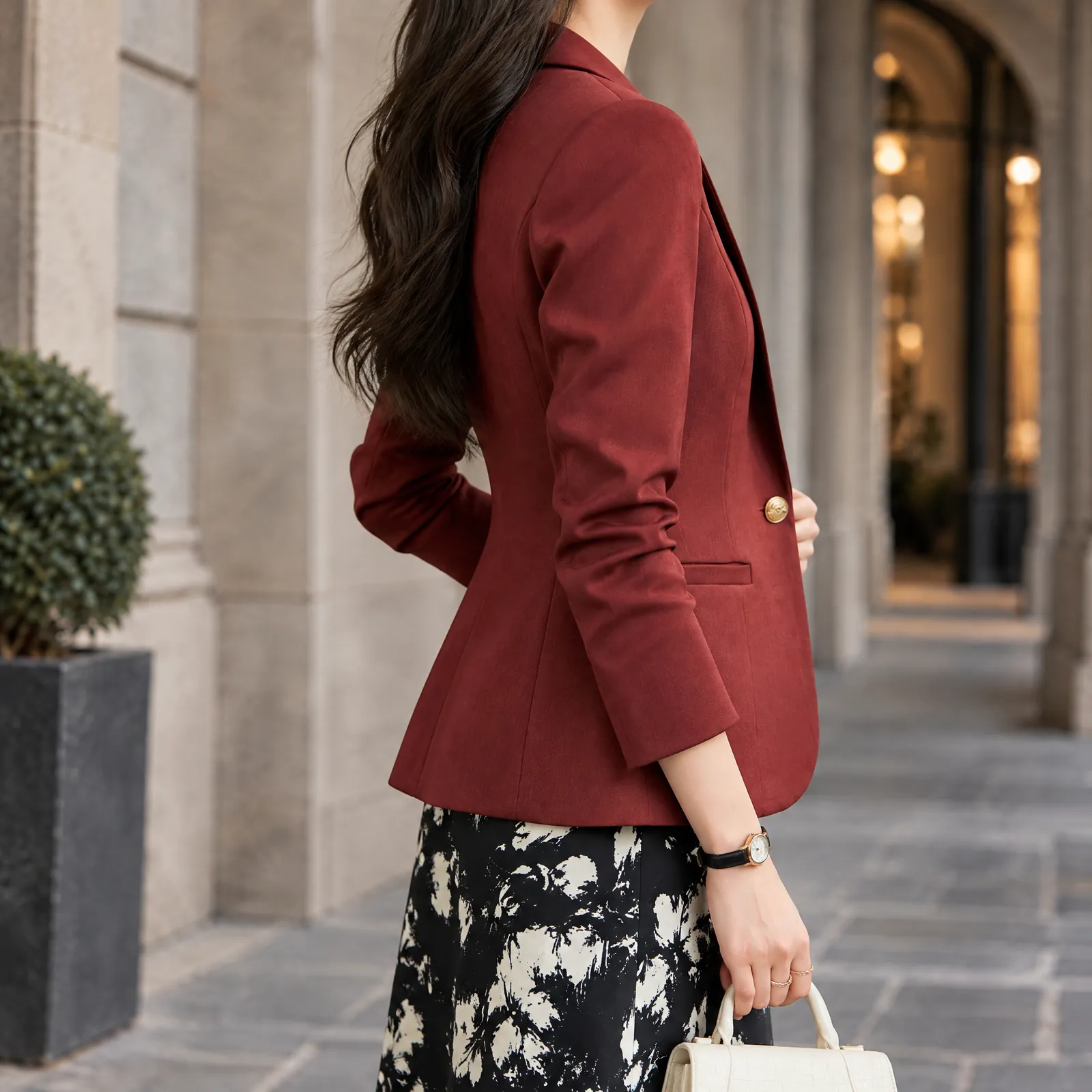 Burgundy blazer worn with a patterned skirt, cropped below the face
